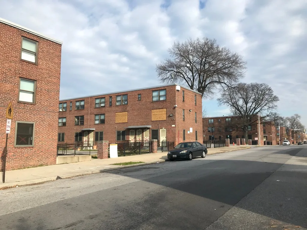 Disused brick apartment buildings with sealed doors and windows along a street.