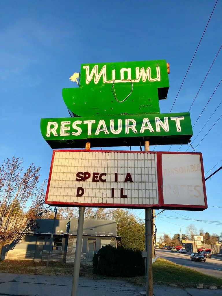 Old sign in front of a closed restaurant with a deteriorated roof.