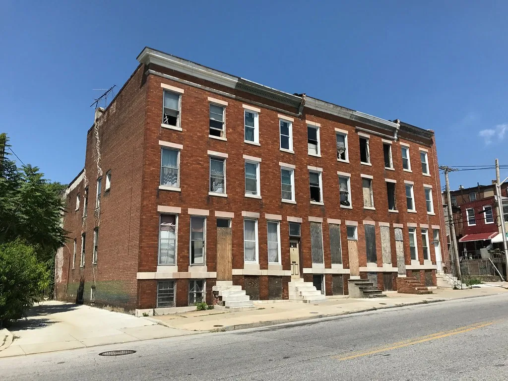Row of red brick houses with boarded windows.