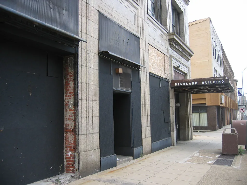 Entrance to an old building with shopfront windows covered by black panels.
