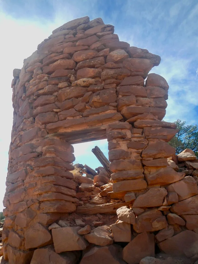 Remnant of a stone tower with an empty opening and fallen blocks.