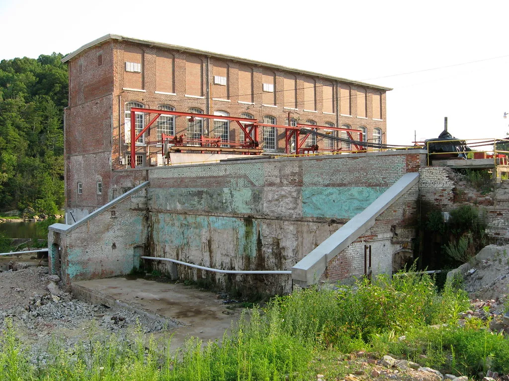 Wall and slab remains in front of an old brick industrial building.