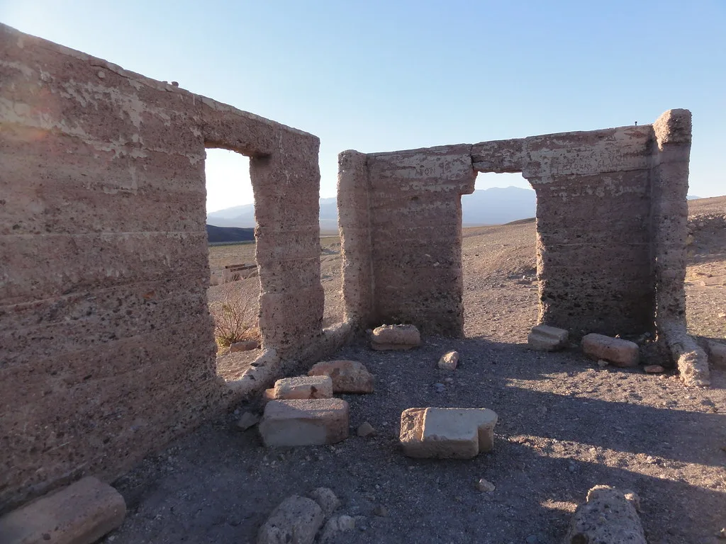 Ruins of ochre walls with two openings in a desert landscape.