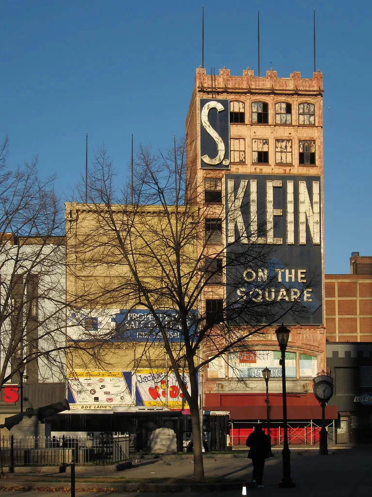 Ancien grand magasin aux fenêtres dégradées sous une enseigne S. Klein.