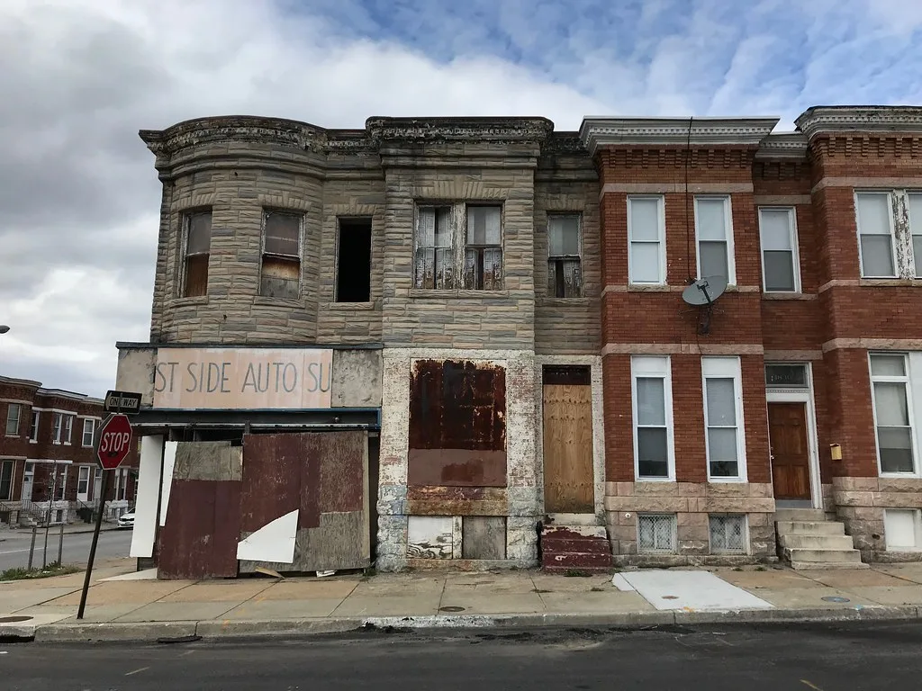 Ancien commerce condamné sous une façade de pierre aux fenêtres dégradées.