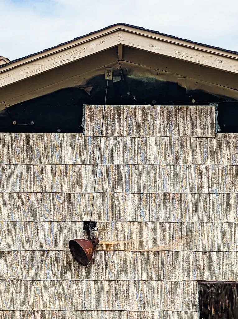 Deteriorated gable with an old light hanging from its cable.