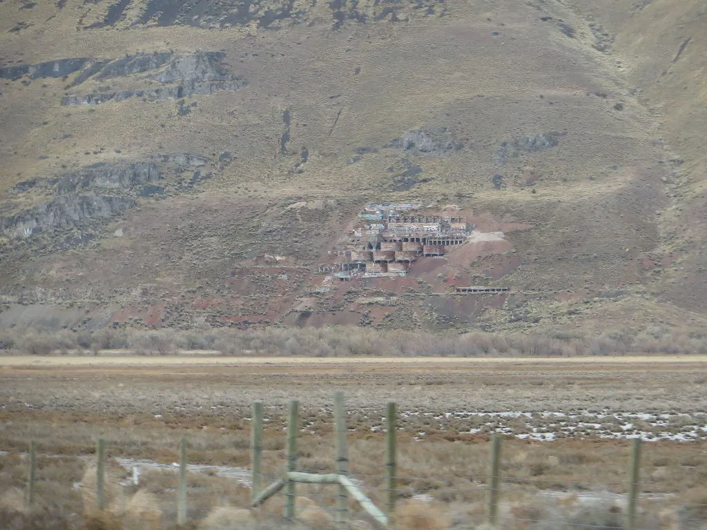 Graffiti-covered industrial ruins on a mountainside.