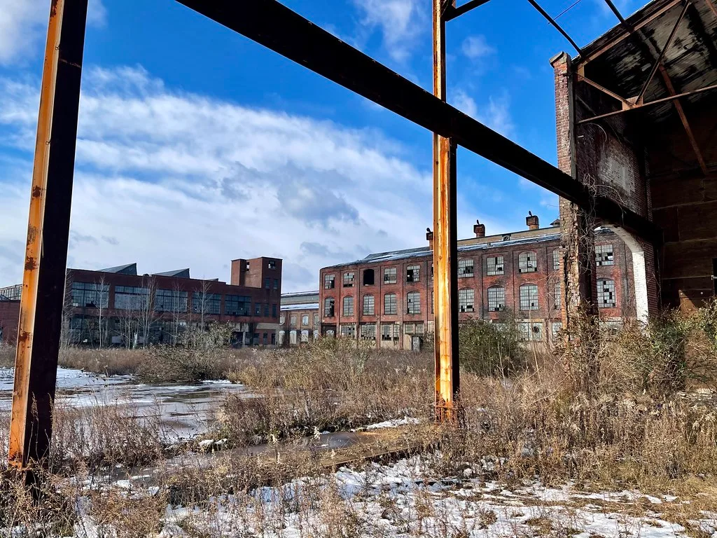 Courtyard of an old factory with broken windows and bare metal structures.