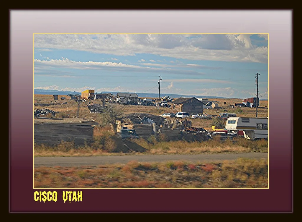 Dilapidated wooden buildings on an arid plain, with a decorative border.