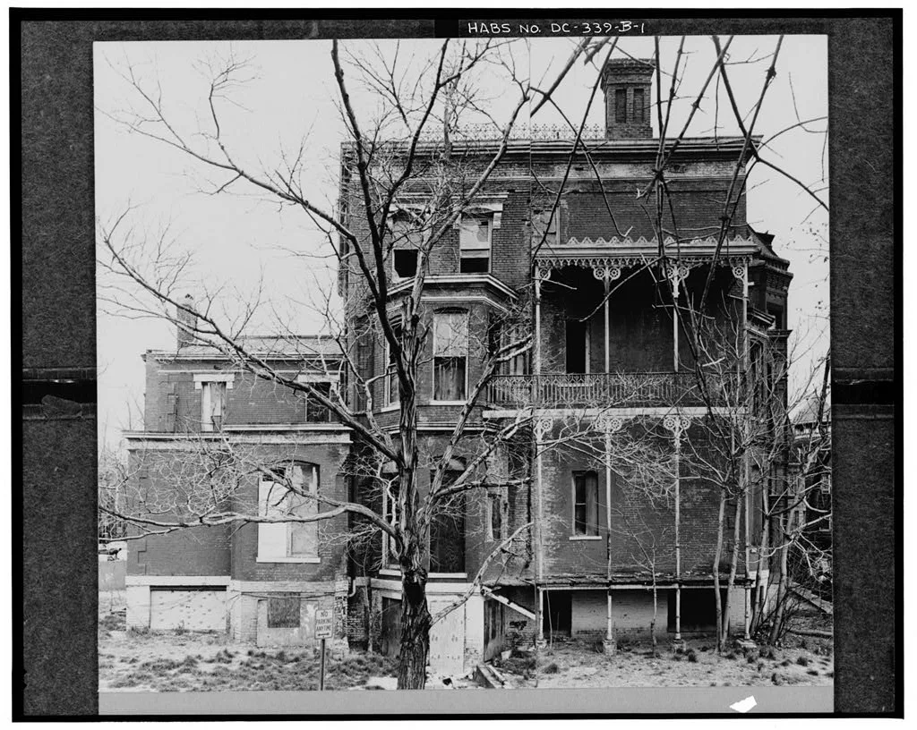 Old photograph of a derelict mansion with ornate balconies and boarded windows.