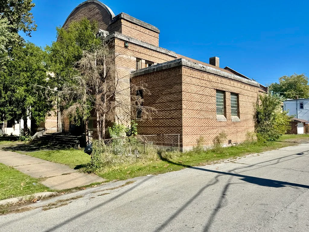 Old brick church behind dense vegetation.