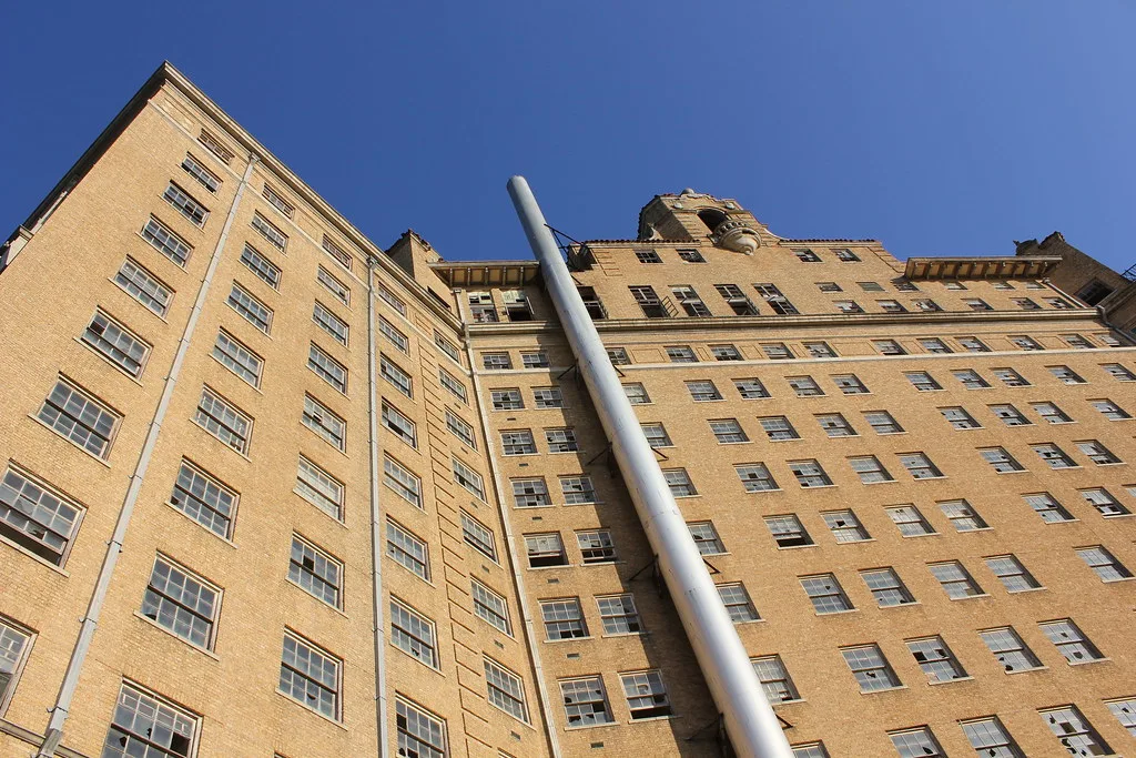 Large yellow-brick building with many broken windows viewed from below.