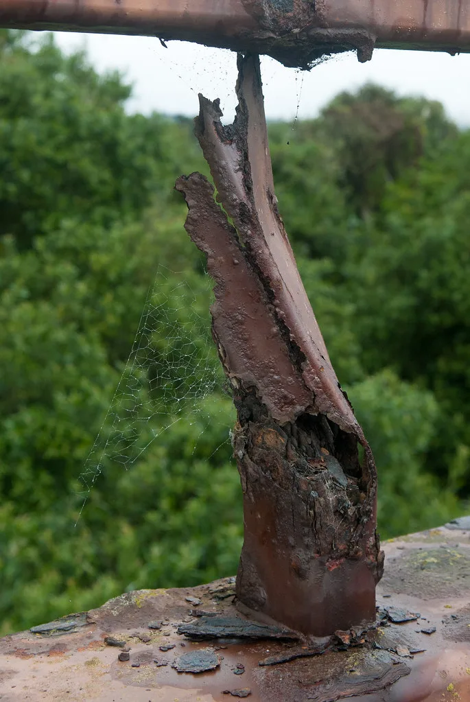 Metal railing post torn open by corrosion.