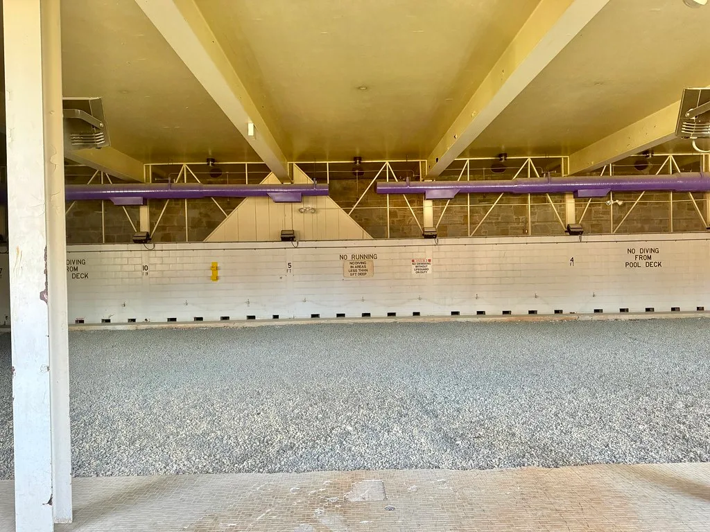 Bassin d’une ancienne piscine intérieure rempli de gravier.
