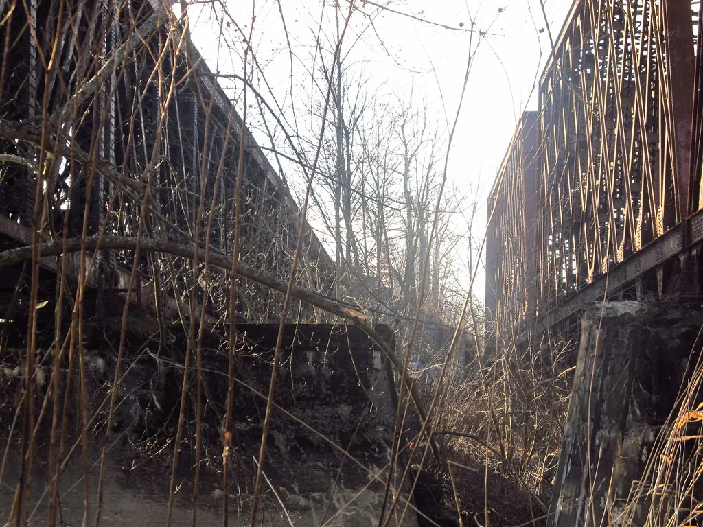 Old metal bridge structures overgrown with vegetation.