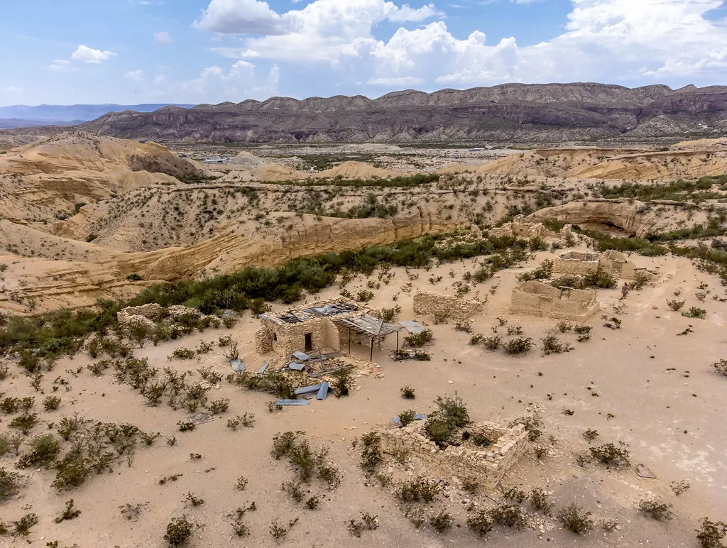 Ruins of stone houses in a hilly desert landscape.