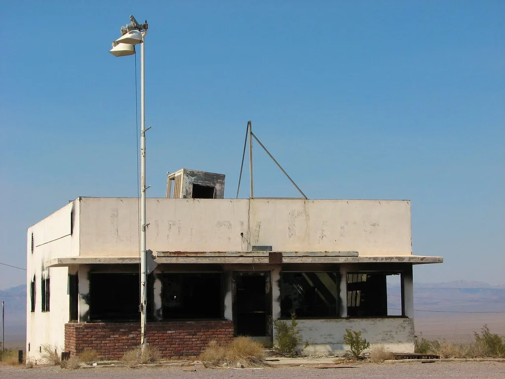 Small abandoned building with large empty openings in an arid landscape.