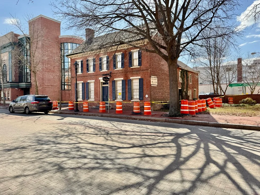 Red-brick John Bullen House in Dover, with blue shutters and safety barrels outside.