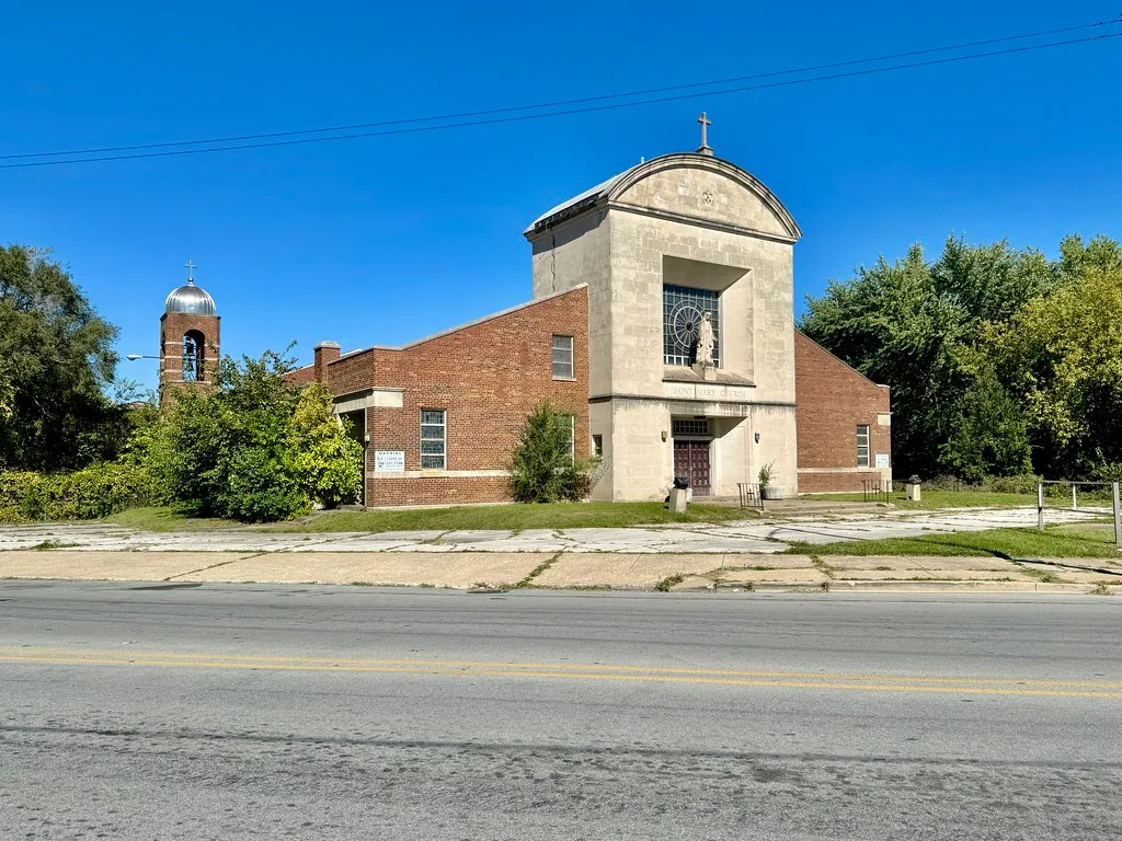Former brick church with a cracked forecourt and overgrown surroundings.