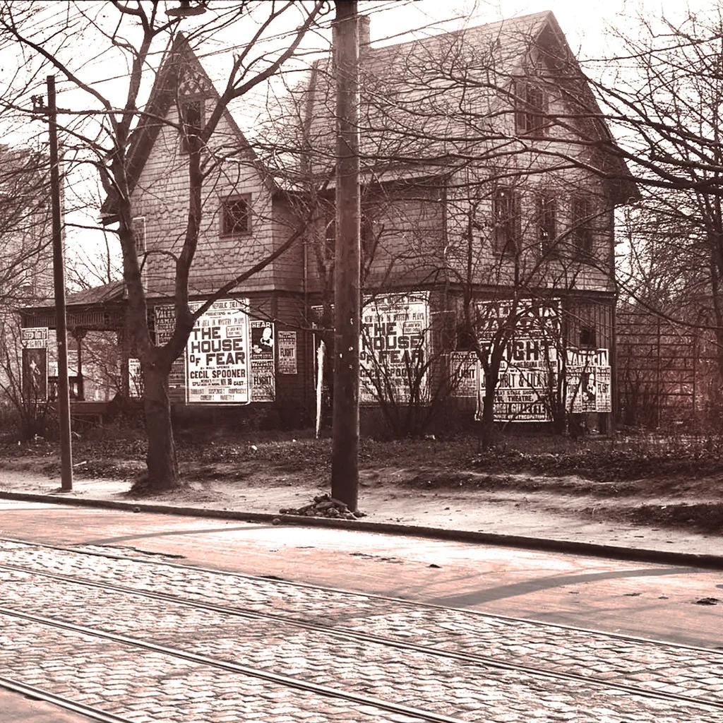 Vue ancienne d’une maison abandonnée aux fenêtres vides et ouvertures basses couvertes d’affiches.