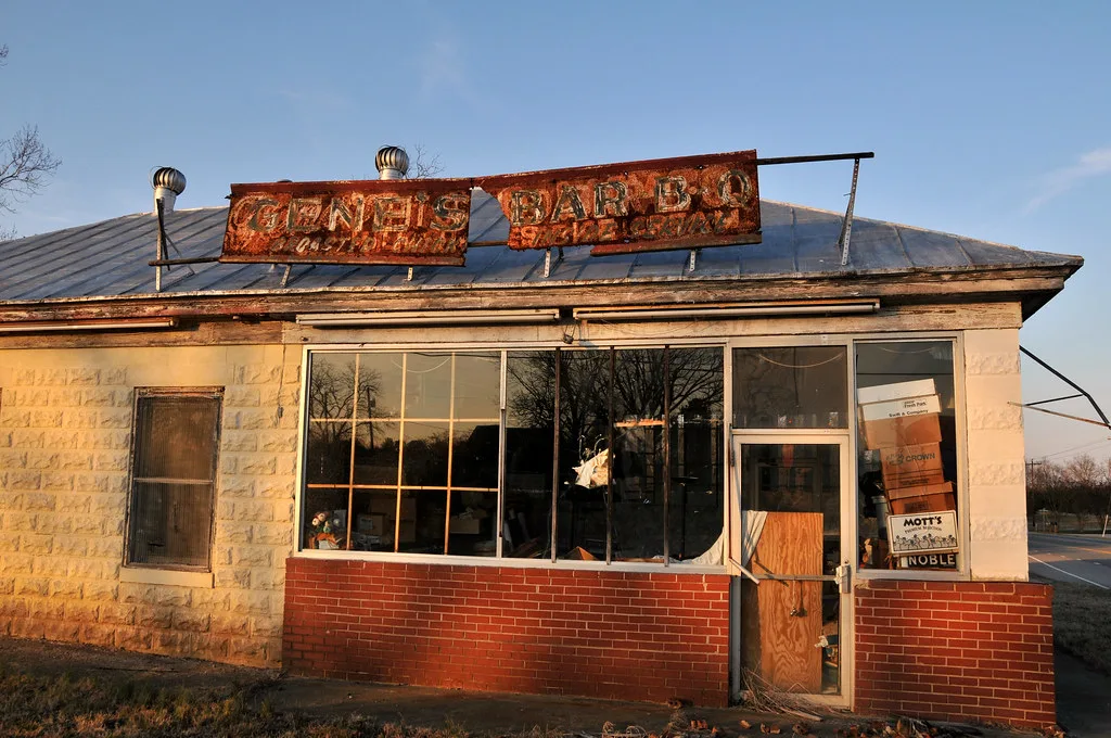Old restaurant with broken glazing beneath a rusted sign.