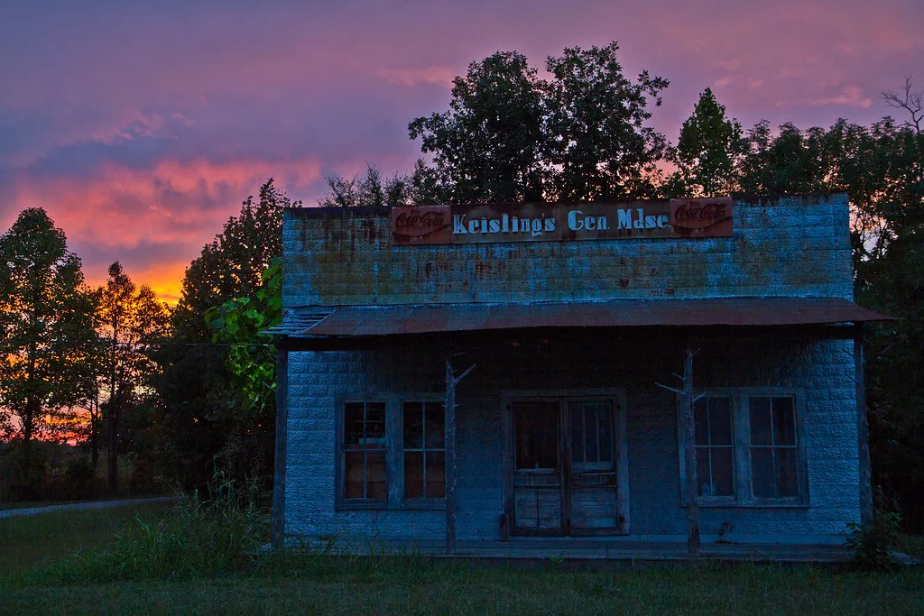 Ancienne boutique de bois à façade bleue usée au coucher du soleil.