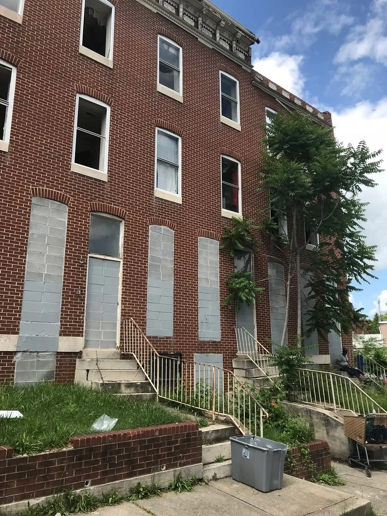 Anciennes maisons de briques aux entrées murées et fenêtres brisées.