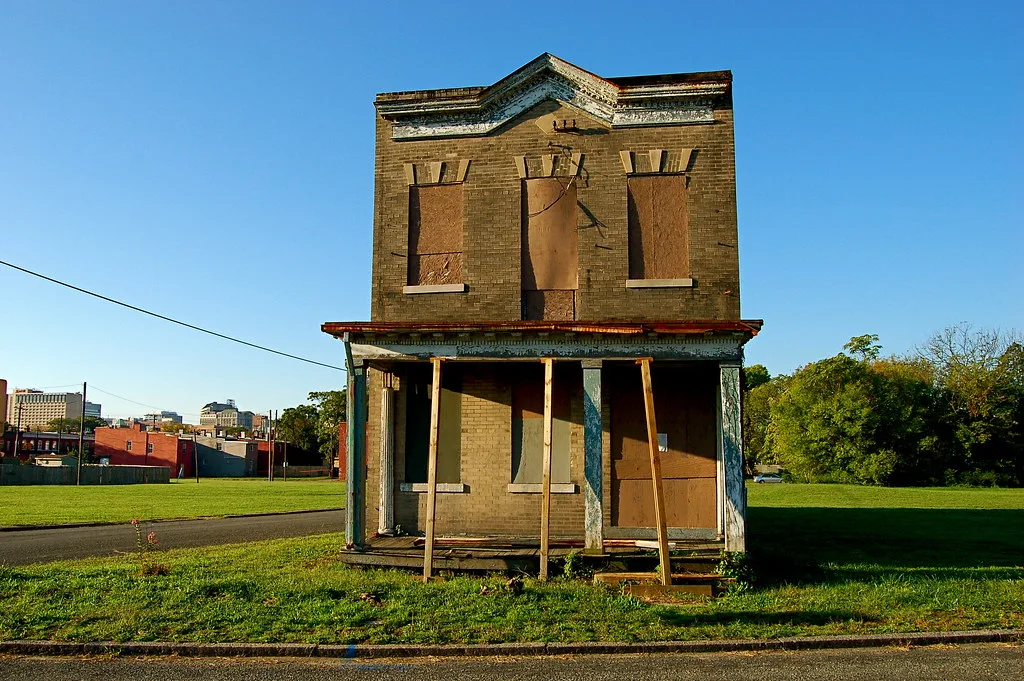 Isolated old building with boarded windows and a propped-up porch.