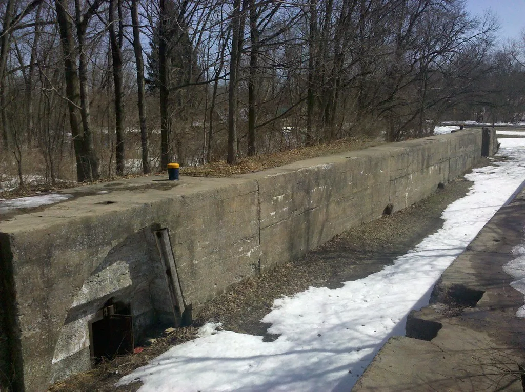 Old dry lock with masonry walls, partly covered in snow.