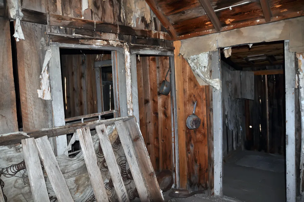 Old bed in a room with decaying wooden walls.