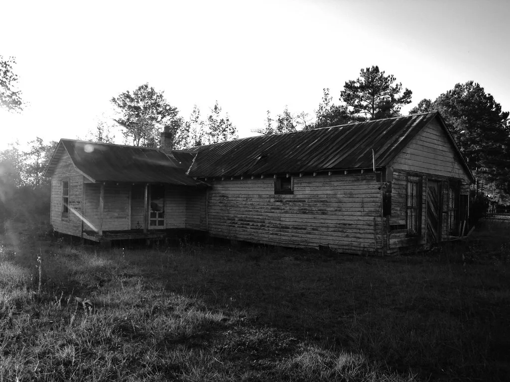 Deteriorated old wooden building in tall grass.