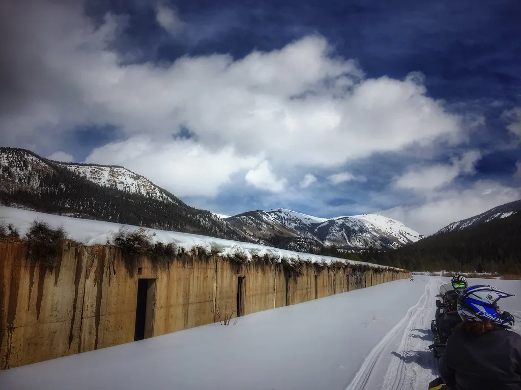 Snow-covered old concrete structure in a mountain valley.