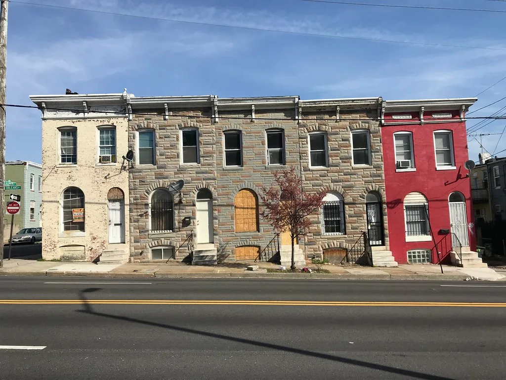 Rowhouses on Orleans Street in Baltimore with several boarded openings.