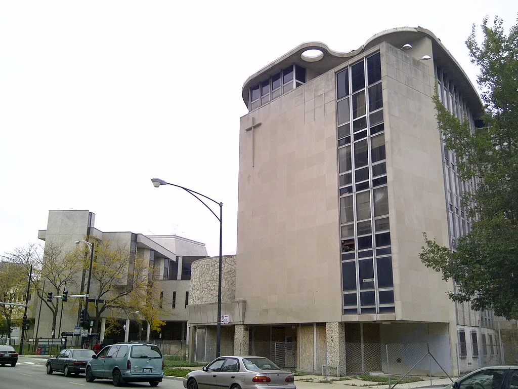 Old building with a curved roof and damaged windows behind a fence.