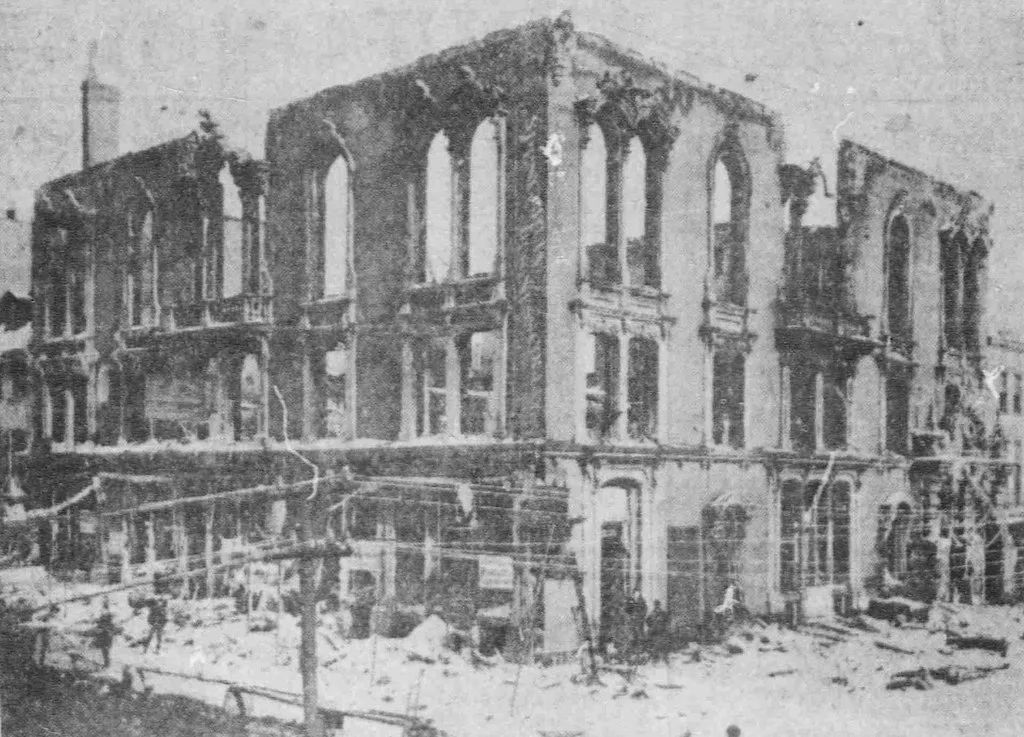 Old black-and-white photograph of a roofless ruined building with large empty windows and rubble at the foot of its facades.