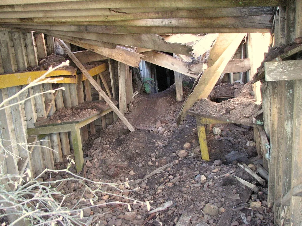 Broken beams and earth inside a collapsed old wooden structure.