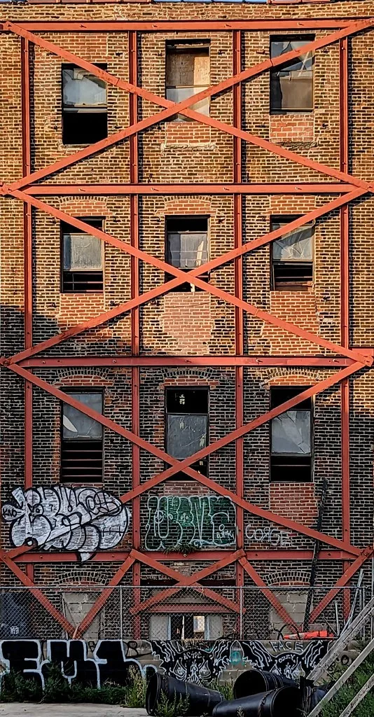 Brick facade reinforced with red beams and broken windows.