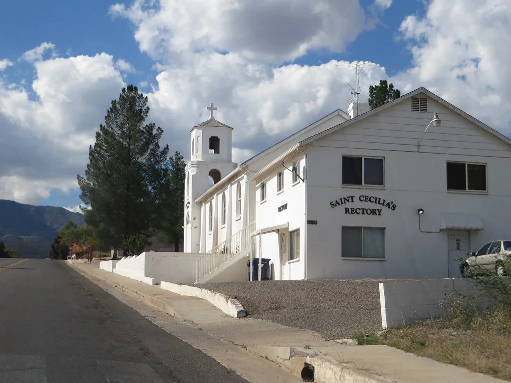 Saint Cecilia rectory and bell tower in Clarkdale alongside a street.