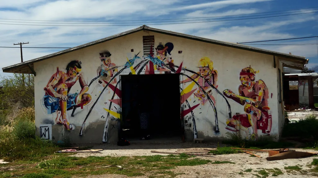 Small open building covered with a mural of figures.