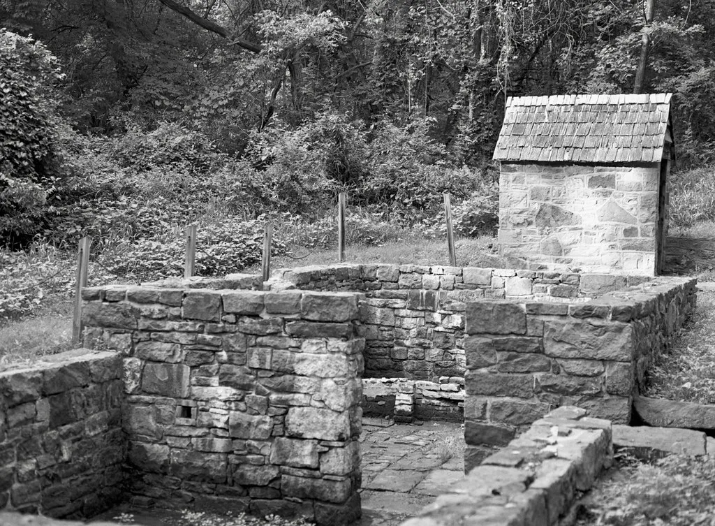 Remains of stone walls beside a small roofed structure.