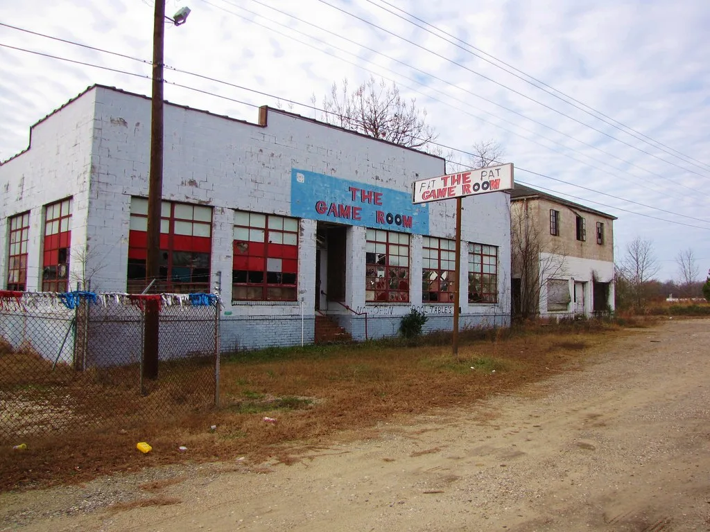 Former games room with large broken windows and a white façade.