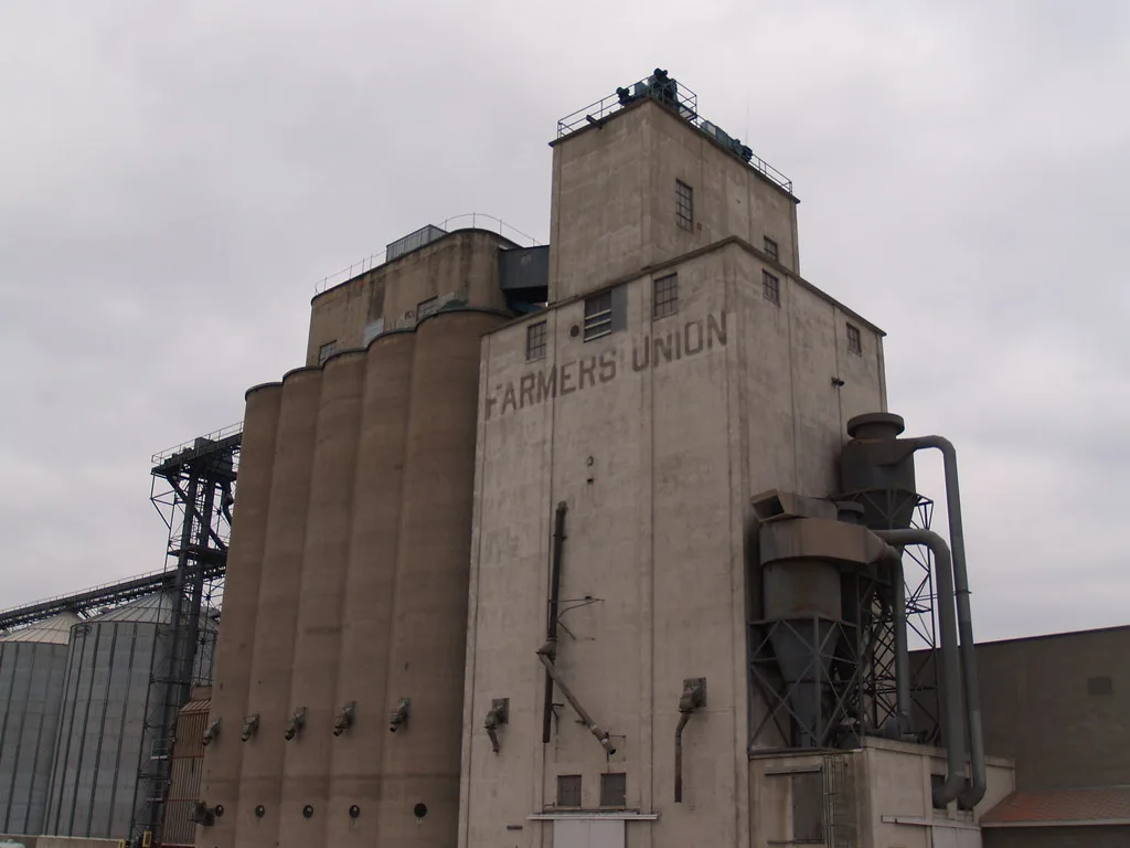 Old concrete grain elevator with silos and exterior pipework.