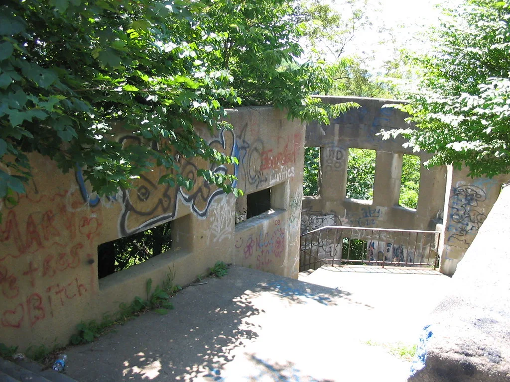 Old concrete staircase surrounded by graffiti-covered walls and trees.