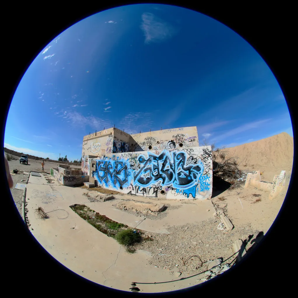 Graffiti-covered ruins in a circular wide-angle view.