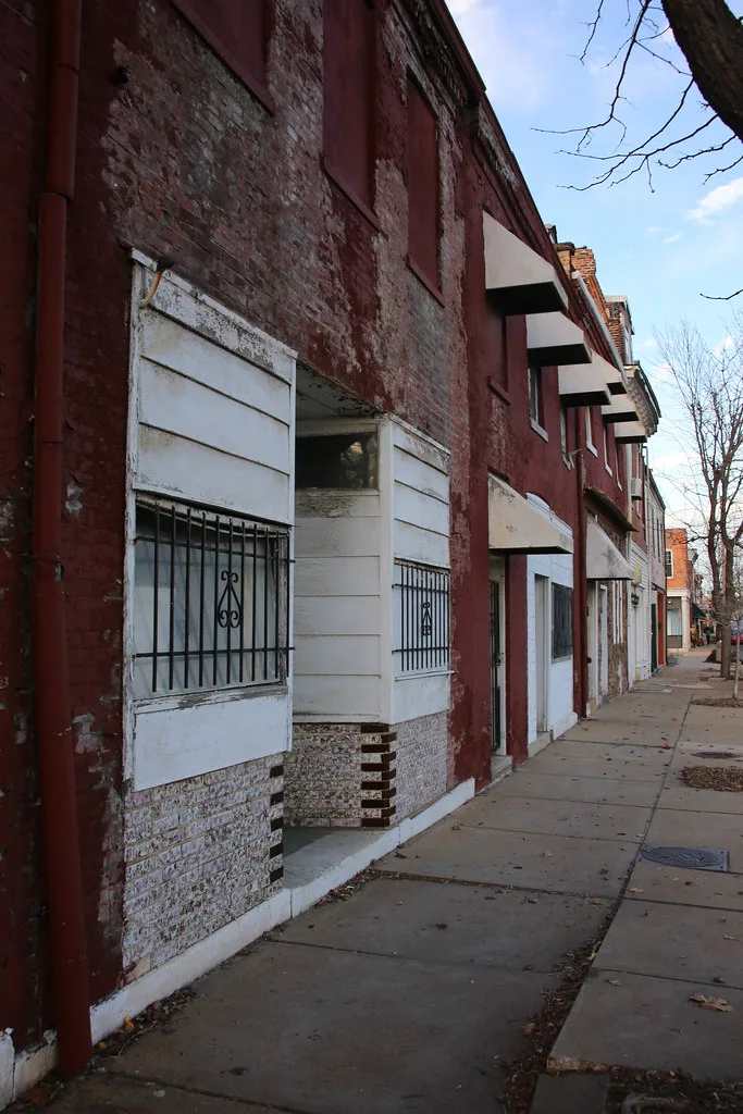 Red and white commercial facades with boarded openings.