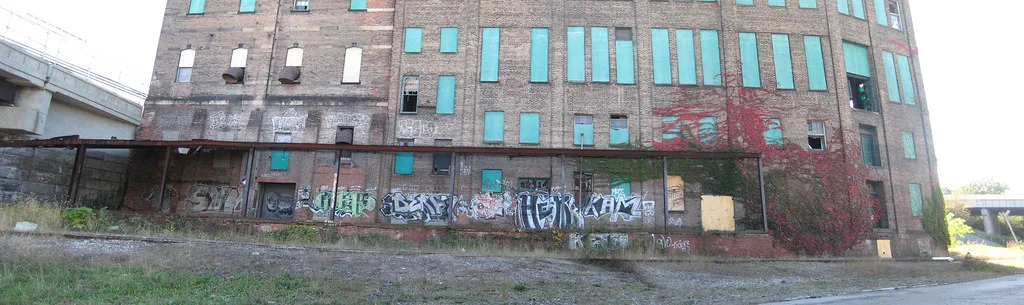 Ancien entrepôt de briques aux fenêtres condamnées et au quai couvert de graffitis.
