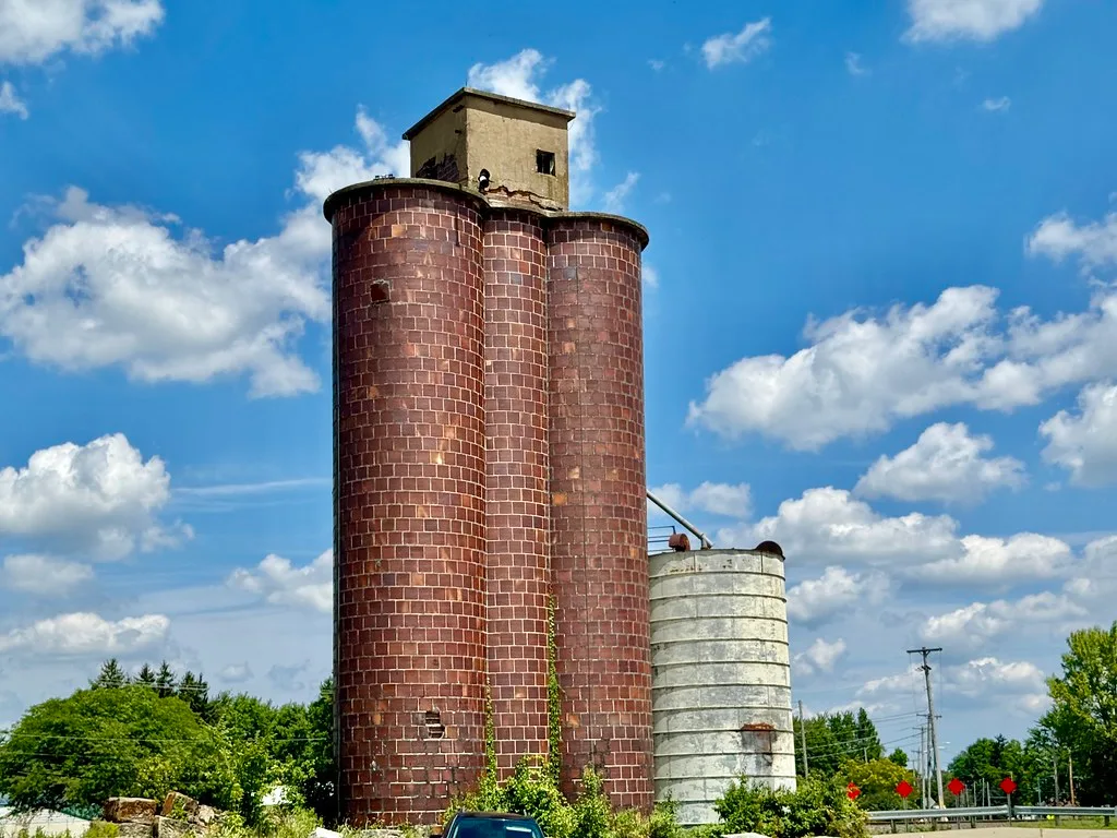Two red brick silos beside a concrete silo.