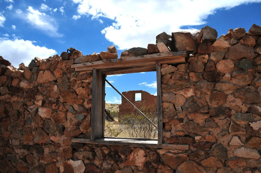 Ruined stone wall with an empty window framing further remains.