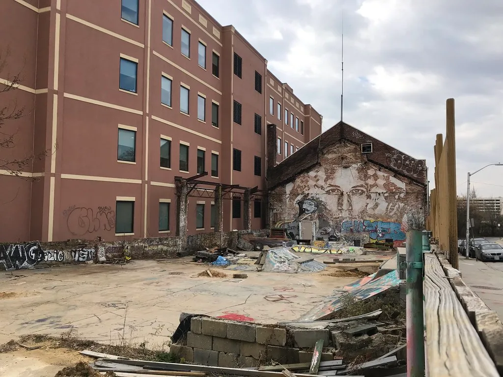 Dilapidated old yard with ramps and a wall bearing a large face mural.