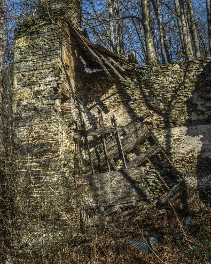 Collapsed wooden floors between the stone walls of a ruin.
